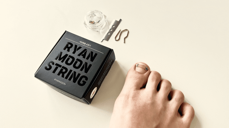 라이언문 내성발톱 교정기를 착용한 발과 도구 및 포장이 베이지 배경 위에 놓여 있음. 내성발톱 교정기 후기