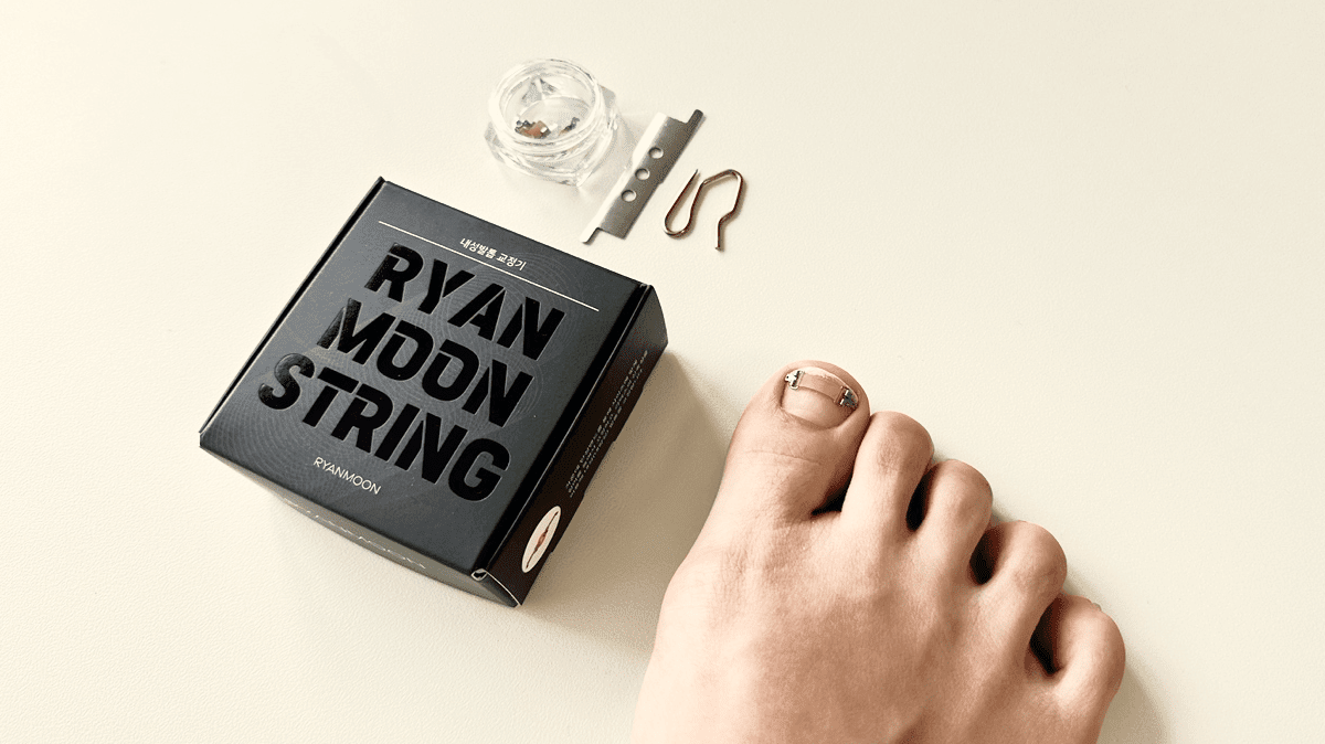 라이언문 내성발톱 교정기를 착용한 발과 도구 및 포장이 베이지 배경 위에 놓여 있음. 내성발톱 교정기 후기